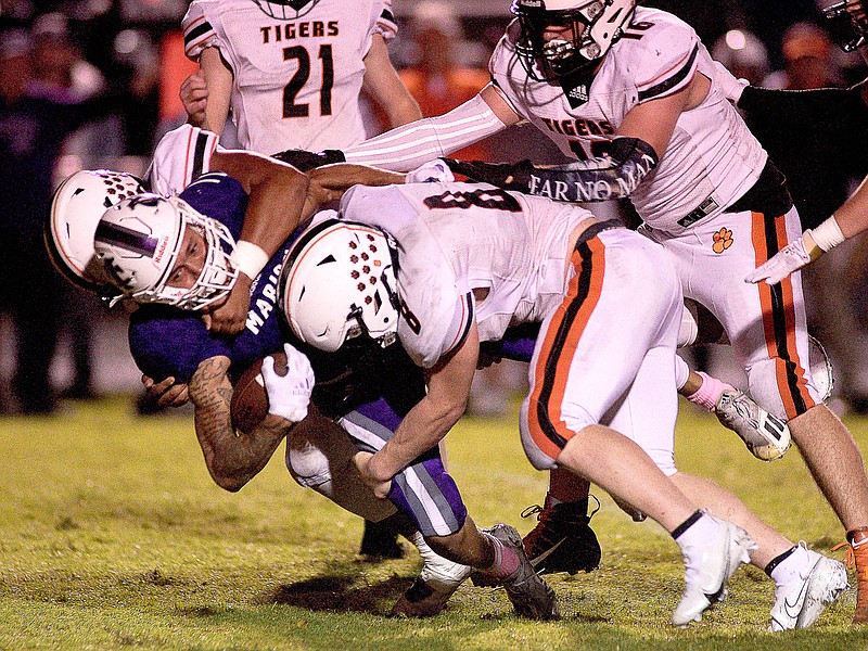 Staff photo by Robin Rudd / Meigs County's Benjamin Smith (8) and Daqwan Tatum stop Marion County's Rylee Rogers for a loss Friday night.