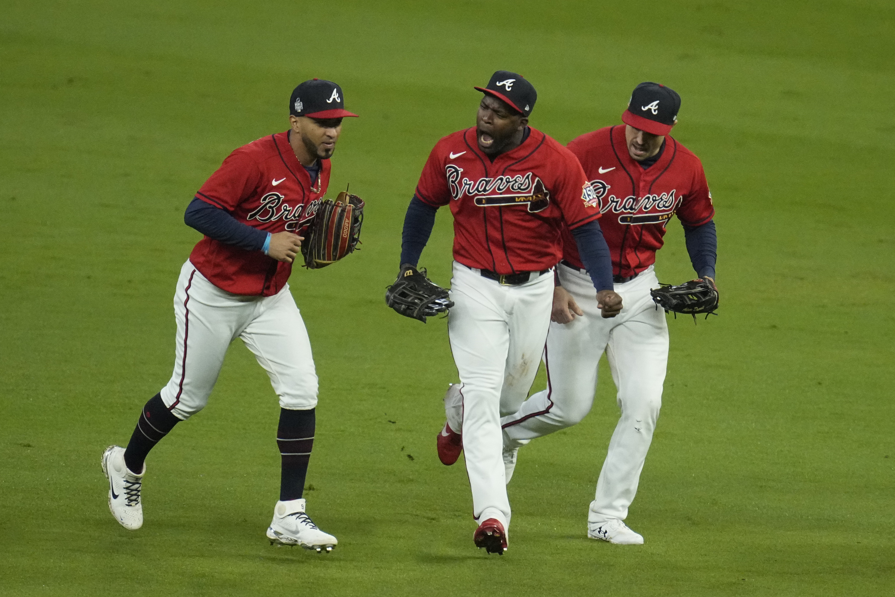 Atlanta Braves left fielder Eddie Rosario, left, and Guillermo Heredia and Adam Duvall celebrate after their win in Game 3 of baseball's World Series between the Houston Astros and the Atlanta Braves Friday, Oct. 29, 2021, in Atlanta. The Braves won 2-0, to lead the series 2-1games. (AP Photo/Ashley Landis)