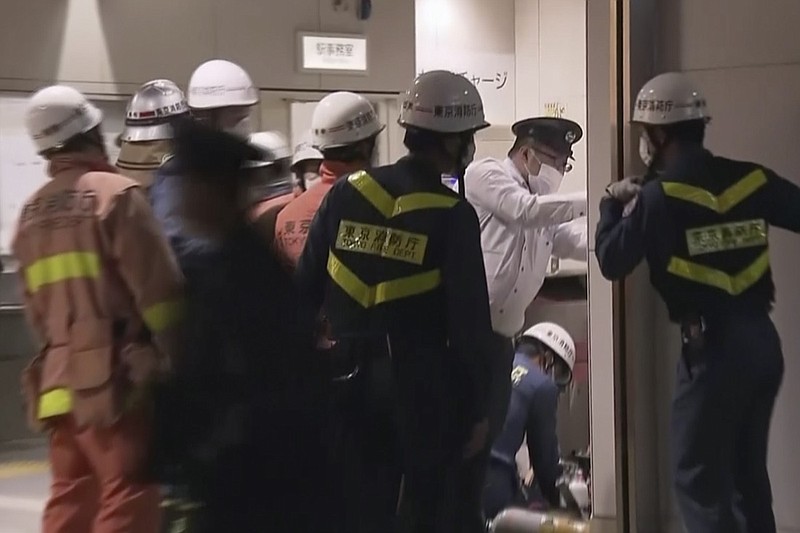 Emergency workers and police investigate the scene at a train station in Tokyo on Sunday, Oct. 31, 2021, after a man brandishing a knife on a commuter train stabbed several passengers before starting a fire, which sent people scrambling to escape and jumping from windows, police and witnesses said. (NTV via AP)
