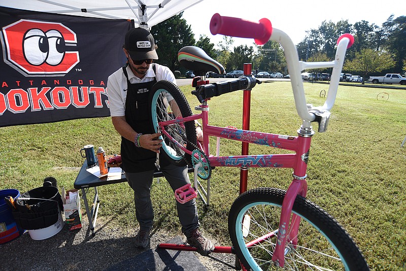 Staff Photo by Matt Hamilton / Blake Pierce, director of the White Oak Bicycle Co-op, works on a bike during a pop-up bike giveaway in White Oak Park in Red Bank.