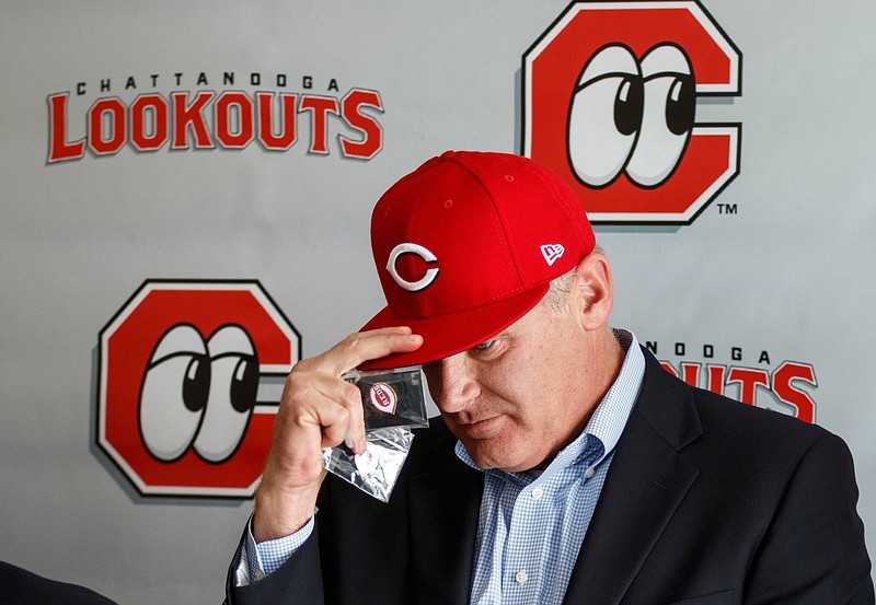 Staff photo by Doug Strickland / Chattanooga Lookouts co-owner John Woods puts on a Cincinnati Reds hat during a news conference announcing the renewed partnership between the Lookouts and the Reds held at AT&T Stadium on Tuesday, Sept. 25, 2018, in Chattanooga, Tenn.