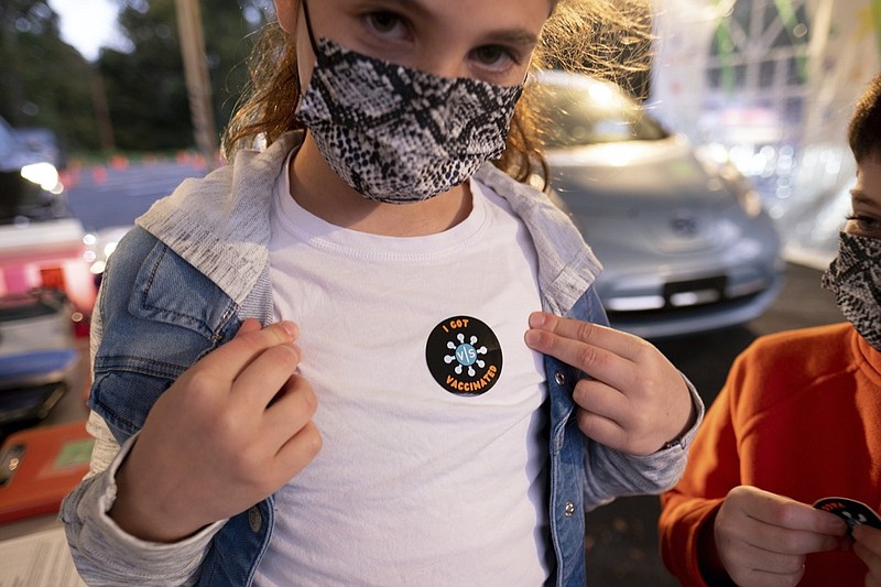 Leah Lefkove, 9, shows off her vaccination sticker just before being the first child to be vaccinated at the Viral Solutions vaccination and testing site in Decatur, Ga., on the first day COVID-19 vaccinations were available for children from 5 to 12 on Wednesday, Nov. 3, 2021. The U.S. enters a new phase Wednesday in its COVID-19 vaccination campaign, with shots now available to millions of elementary-age children in what health officials hailed as a major breakthrough after more than 18 months of illness, hospitalizations, deaths and disrupted education. (AP Photo/Ben Gray)