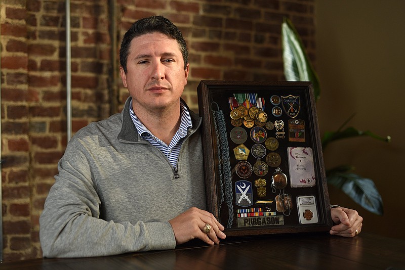 Staff Photo by Matt Hamilton / James Purgason is pictured Tuesday, Nov. 2, 2021, at his office at Market Street Partners displaying a shadow box containing medals and memorabilia from his service in the U.S. Army.