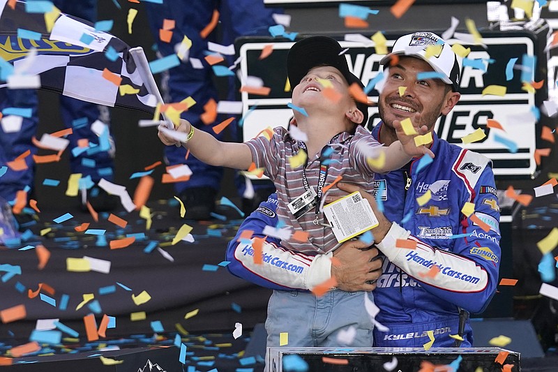 AP photo by Rick Scuteri / Hendrick Motorsports driver Kyle Larson holds his son Owen as they celebrate his victory Sunday at Phoenix Raceway to win the NASCAR Cup Series championship.