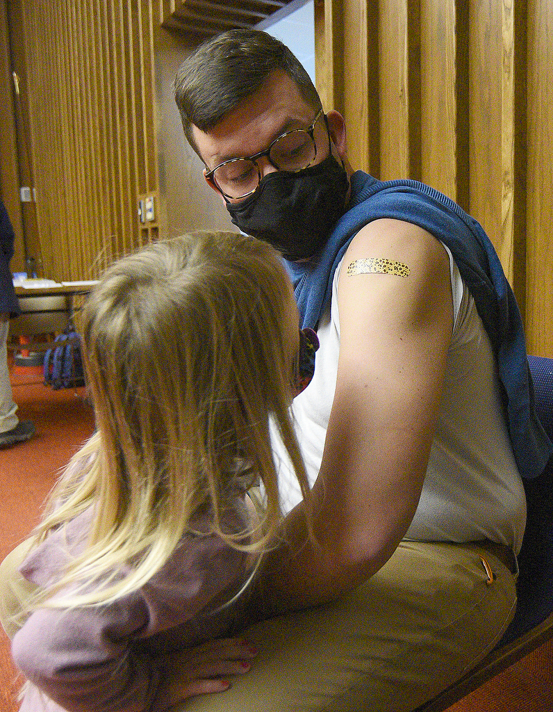 Staff Photo by Matt Hamilton / Chattanooga resident Isla Holland, 4, looks at the bandaid on the arm of her dad, Matt, after he recieved his COVID booster shot from nurse practitioner Meghan Whitehead on Friday, November 13, 2021 at the downtown branch of the Chattanooga Public Library. Lifespring Community Health was providing vaccination shots to children as young as five years old on Friday.