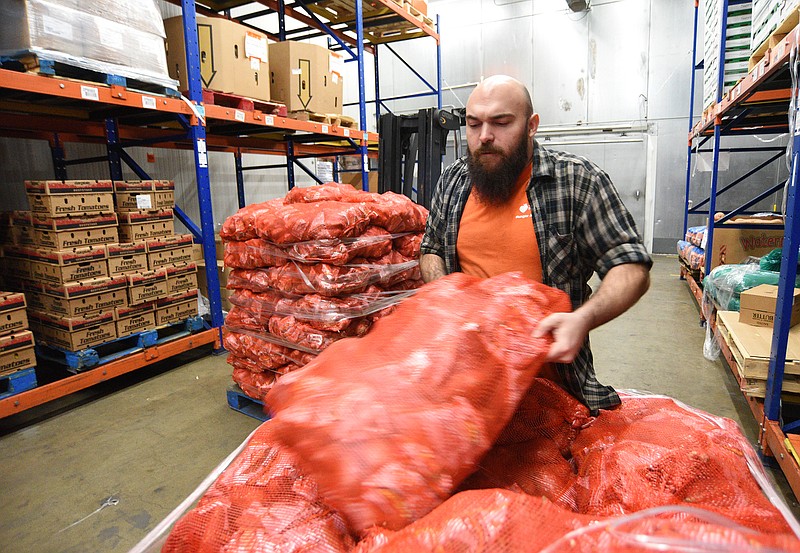 Staff Photo by Matt Hamilton / Red Bank resident Sam Snyder moves a pallet of sweet potatoes in the refrigerated area of the Chattanooga Area Food Bank on Friday.