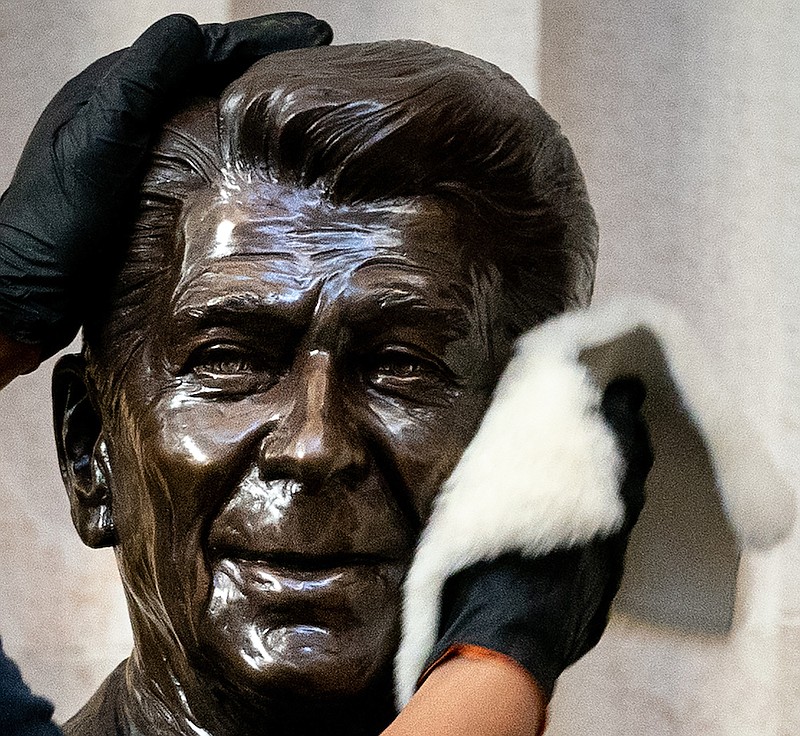 Photo by Erin Schaff of The New York Times / A worker cleans a statue of former President Ronald Reagan at the Capitol Rotunda in Washington on Jan. 12, 2021.