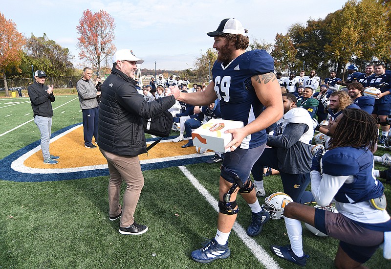 Staff Photo by Matt Hamilton / Luke DeRouen, left, chief marketing officer with Walk-On's Sports Bistreaux, shakes hands with senior Cole Strange after the Mocs practice on Tuesday, November 16, 2021 at Scrappy Moore Field. Senior Cole Strange was chosen to play in the Senior Bowl, an opportunity to be seen by scouts and possibly play in the NFL. 