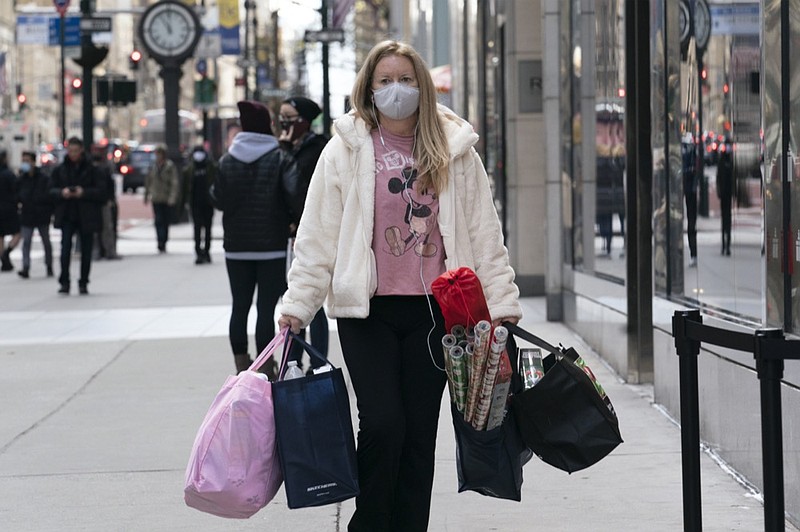 FILE - In this Dec. 10, 2020 file photo, a woman carries shopping bags in New York. (AP Photo/Mark Lennihan, File)


