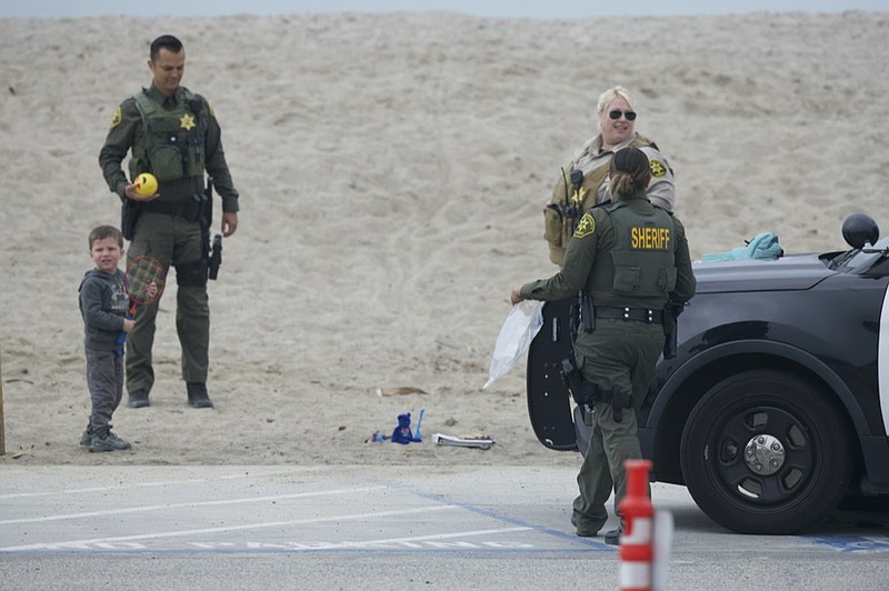 A missing 3-year-old boy from Tennessee stands on the beach with Orange County Sheriffs Deputies at Doheny State Beach in Dana Point, Calif. on Thursday, Nov. 18, 2021. (Patrick Smith via AP)


