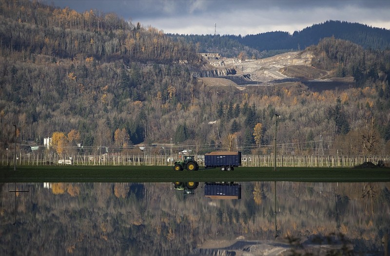 A tractor tows a trailer full of feed past flooded farmland following heavy rains in Abbotsford, British Columbia, Friday, Nov. 19, 2021. (Darryl Dyck/The Canadian Press via AP)

