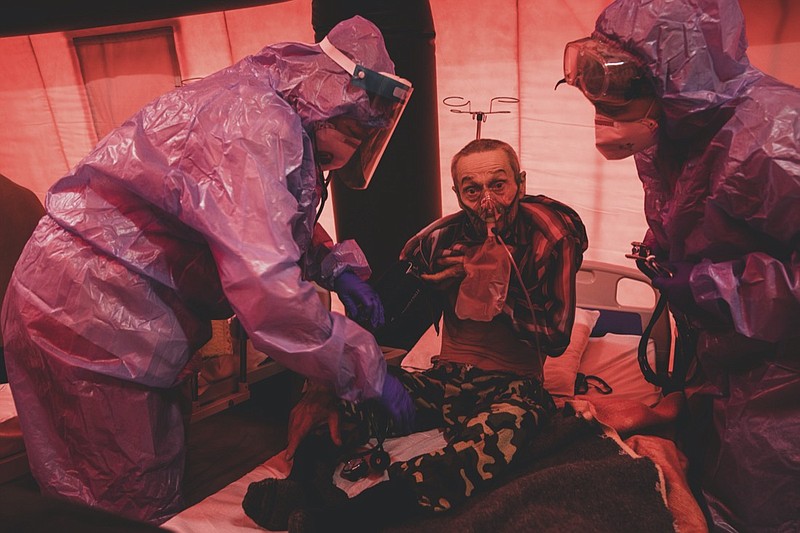 Medical staff treat a coronavirus patient in tents, erected adjacent to a hospital in the city of Kakhovka, Ukraine, on Sunday, Oct. 31, 2021. Ukraine has one of Europe's lowest vaccination rates and a struggling and underfunded health care system. It is setting records almost daily for COVID-19 infections and deaths. (AP Photo/Evgeniy Maloletka)