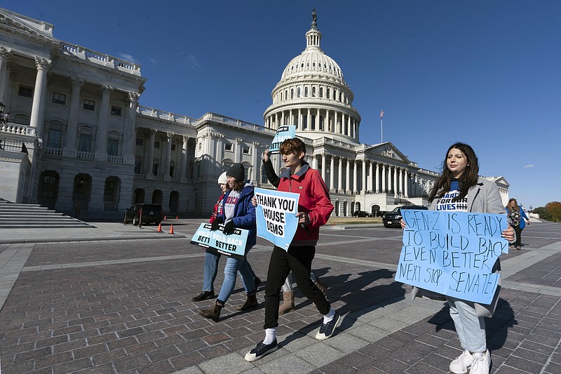 File photo by Manuel Balce Ceneta of The Associated Press / Supporters of the Build Back Better Act walk with their placard outside the Capitol in Washington on Friday, Nov. 19, 2021.