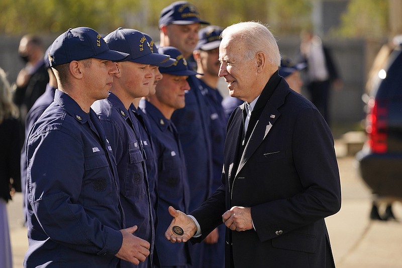 President Joe Biden hands out a challenge coin as he speaks with members of the coast guard at the United States Coast Guard Station Brant Point in Nantucket, Mass., Thursday, Nov. 25, 2021. (AP Photo/Carolyn Kaster)