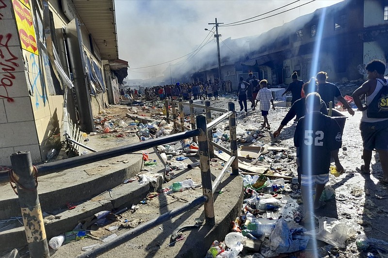 People walk through the looted streets of Chinatown in Honiara, Solomon Islands, Friday, Nov. 26, 2021. (AP Photo/Piringi Charley)


