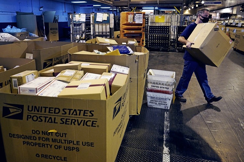 A worker carries a large parcel at the United States Postal Service sorting and processing facility, Thursday, Nov. 18, 2021, in Boston. (AP Photo/Charles Krupa)


