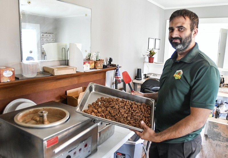 Tim Williams, owner the Nut House Pecan Company in Byron, Ga.,holds up a pan of praline pecans on Nov. 18, 2021. Williams, 32, opened a storefront in a converted old home and the Nut House Pecan Company was born. ( Jason Vorhees /The Macon Telegraph via AP)