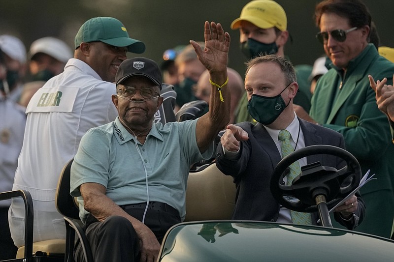 FILE - Lee Elder waves as he arrives for the ceremonial tee shots before the first round of the Masters golf tournament on Thursday, April 8, 2021, in Augusta, Ga. At far right is Phil Mickelson. Person at right in cart is unidentified. Elder broke down racial barriers as the first Black golfer to play in the Masters and paved the way for Tiger Woods and others to follow. The PGA Tour confirmed Elder's death, which was first reported by Debert Cook of African American Golfers Digest. No cause or details were immediately available, but the tour said it spoke with Elder's family. He was 87. (AP Photo/Charlie Riedel, File)