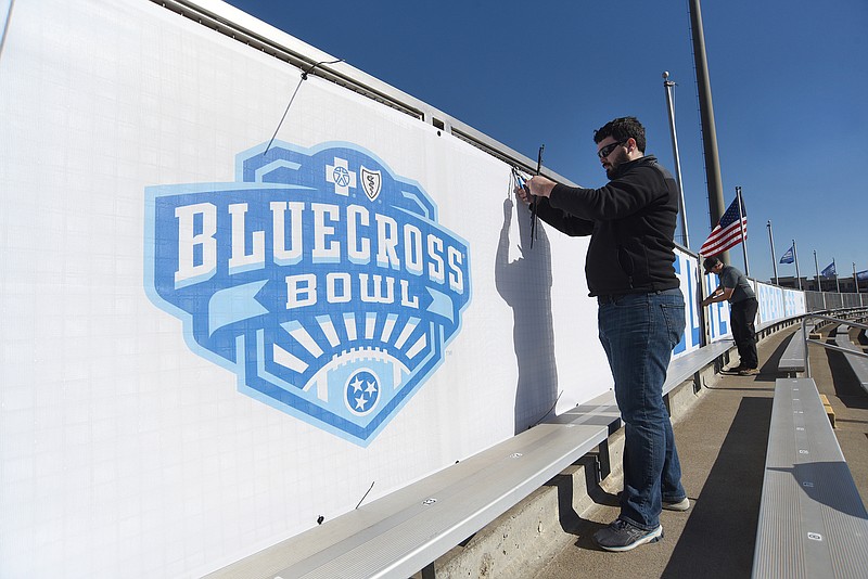 Staff photo by Matt Hamilton / Brandon Wilson with Vincent Printing helps put up a banner at Finley Stadium on Tuesday. The TSSAA's nine BlueCross Bowl football state championship games will be held at the stadium this week, with three each on Thursday, Friday and Saturday.