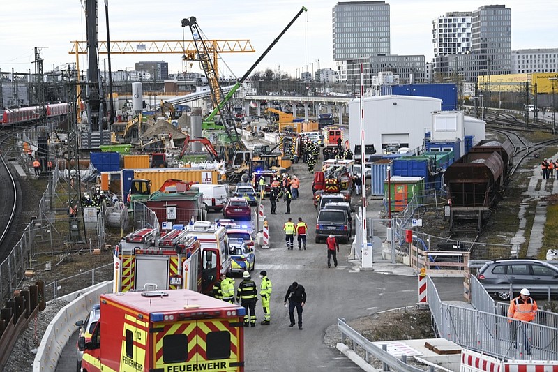 Firefighters, police officers and railway employees stand on a railway site in Munich, Germany, Wednesday, Dec. 1, 2021. Police in Germany say three people have been injured including seriously in an explosion at a construction site next to a busy railway line in Munich. (Sven Hoppe/dpa via AP)