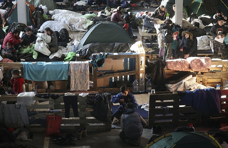 Migrants settle in the logistics center of the checkpoint "Bruzgi" at the Belarus-Poland border near Grodno, Belarus, Wednesday, Dec. 1, 2021. The West has accused Belarusian President Alexander Lukashenko of luring thousands of migrants to Belarus with the promise of help to get to Western Europe to use them as pawns to destabilize the 27-nation European Union in retaliation for its sanctions on his authoritarian government. Belarus denies engineering the crisis. (Oksana Manchuk/BelTA via AP)