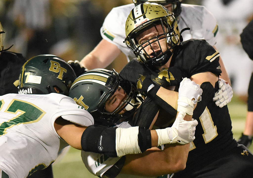 Staff Photo by Matt Hamilton / Calhoun High (21) Caden Williams carries the ball as Blessed Trinity (32) Mavrick Torrico and (27) Dylan Torrico wrap him up on Friday, December 3, 2021 in Calhoun, Ga. Calhoun High hosted Blessed Trinity in a GHSA Class 5A football semifinal game Friday.