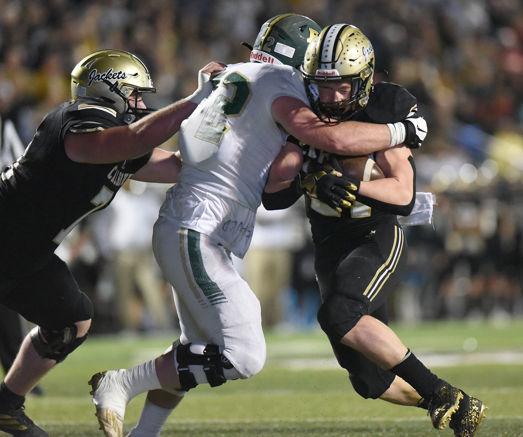 Staff Photo by Matt Hamilton / Calhoun High (21) Caden Williams carries the ball as Blessed Trinity (72) Ryan Scott defends on Friday, December 3, 2021 in Calhoun, Ga. Calhoun High hosted Blessed Trinity in a GHSA Class 5A football semifinal game Friday.