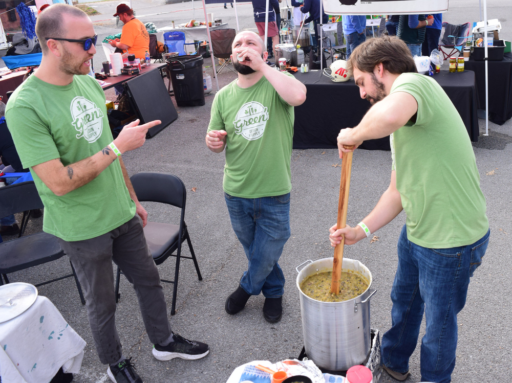 Staff Photo by Robin Rudd / From left, Zach Onusic, Eric Fish and Michael Grilo of Green's Design and Supply and Hill City Chili talks as Mr. Grilo stirs a pot of vegetarian chili. The 15th annual MAINx24 EPB Southside Parade and street festival took place on December 4, 2021.