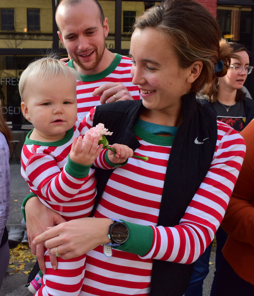 Staff Photo by Robin Rudd / Looking like candy canes little Joanna Kate holds a flower in the arms of her mother, Clara, as father, Rob, looks on. The 15th annual MAINx24 EPB Southside Parade and street festival took place on December 4, 2021.