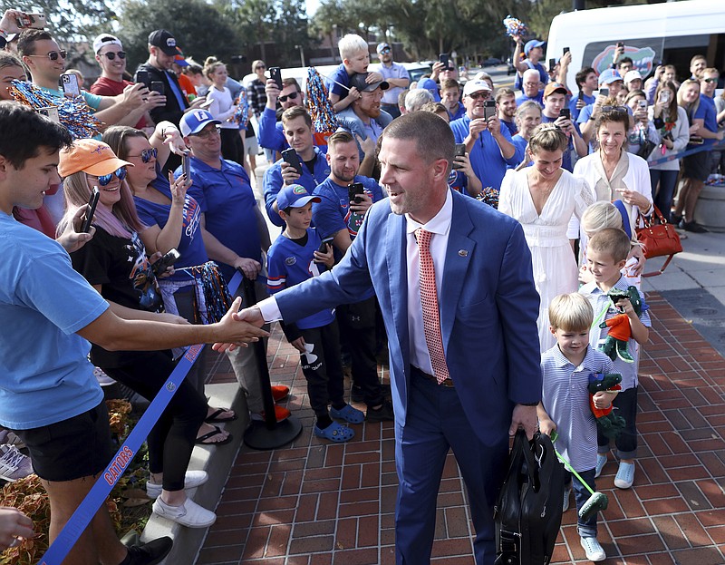 Gainesville Sun photo by Brad McClenny via AP / University of Florida football coach Billy Napier shakes hands with fans as he and his family arrive at Ben Hill Griffin Stadium on Sunday for his introductory news conference in Gainesville.