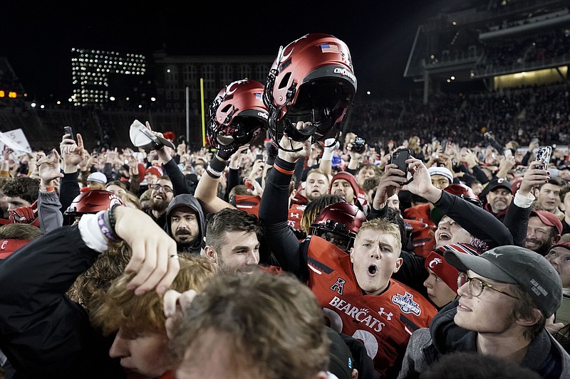 AP photo by Jeff Dean / University of Cincinnati football fans and players celebrate after the Bearcats beat visiting Houston to win the American Athletic Conference championship game on Saturday.