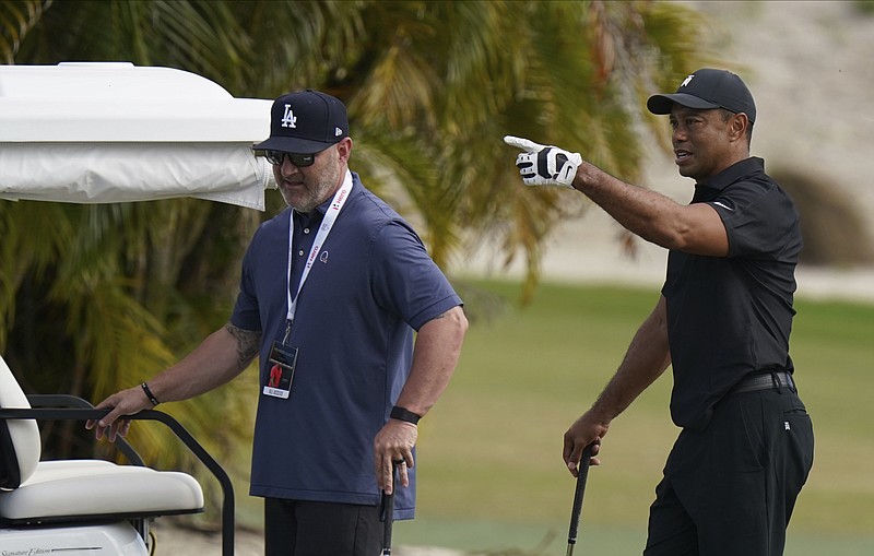 AP photo by Fernando Llano / Tiger Woods, right, speaks with his trainer Kolby Wayne during a practice session at the Albany Golf Club last Saturday in New Providence, Bahamas, where Woods was hosting his annual Hero World Challenge golf tournament.