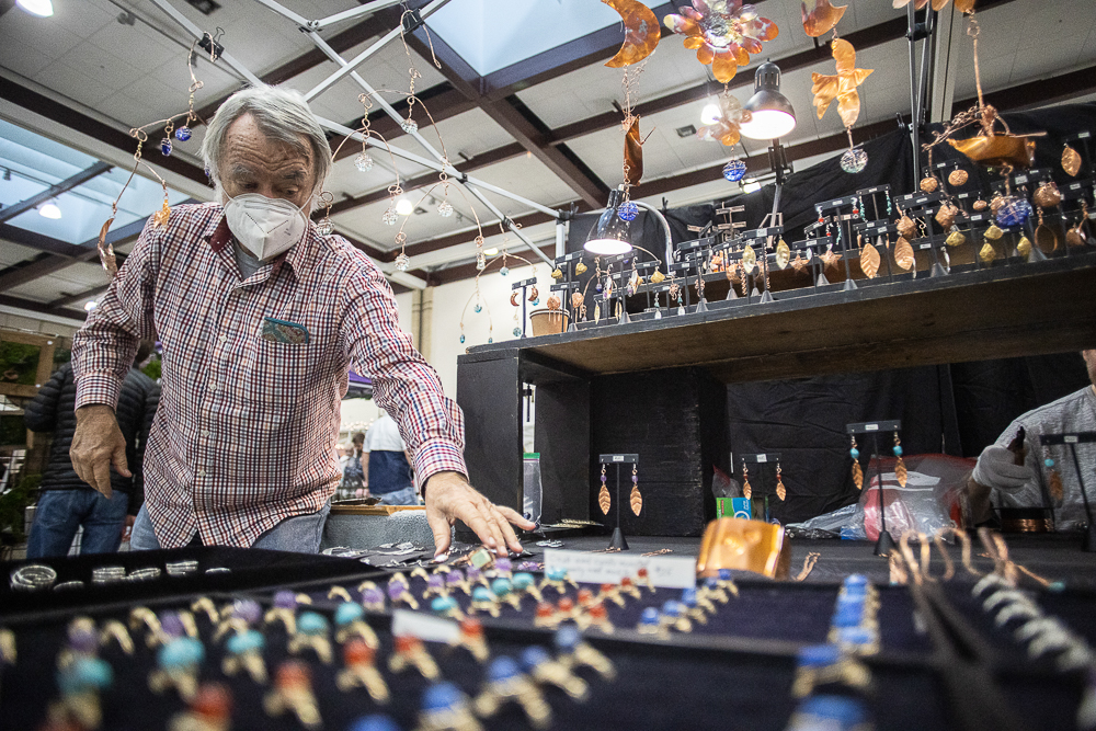 Staff photo by Troy Stolt / John Arnemann adds a new piece to his display of hand made collection of mobiles and jewelry during the Holiday Market at the Chattanooga Convention Center on Saturday, Dec. 11, 2021.