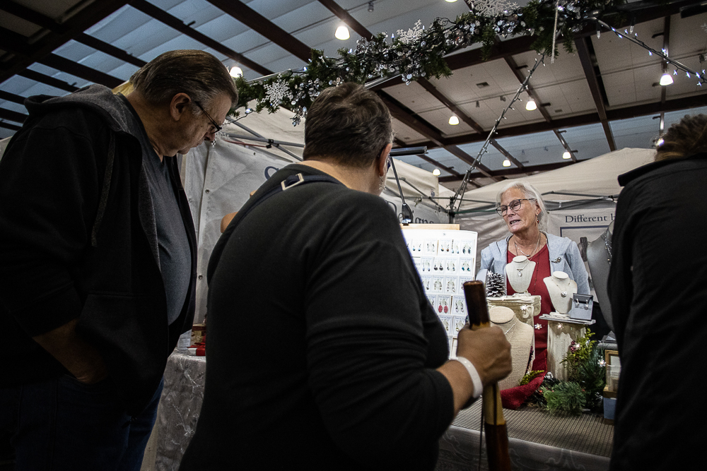 Staff photo by Troy Stolt / Elizabeth Long of StoneLink Designs of Chattanooga helps customers at her booth during the Holiday Market at the Chattanooga Convention Center on Saturday, Dec. 11, 2021.