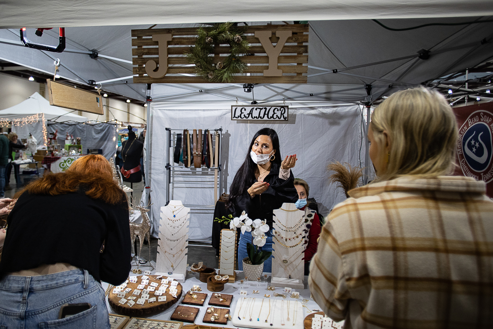 Staff photo by Troy Stolt / Maria Gomez helps customers looking at her jewelry and leather products during the Holiday Market at the Chattanooga Convention Center on Saturday, Dec. 11, 2021.
