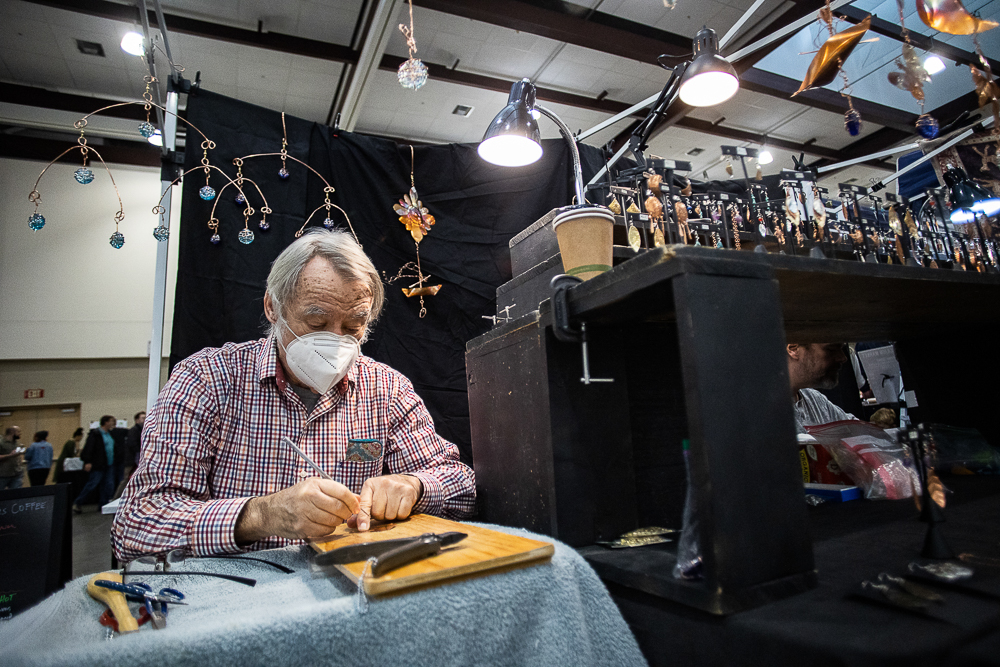 Staff photo by Troy Stolt / John Arnemann works on a new piece to add to his display of hand made collection of mobiles and jewelry during the Holiday Market at the Chattanooga Convention Center on Saturday, Dec. 11, 2021.