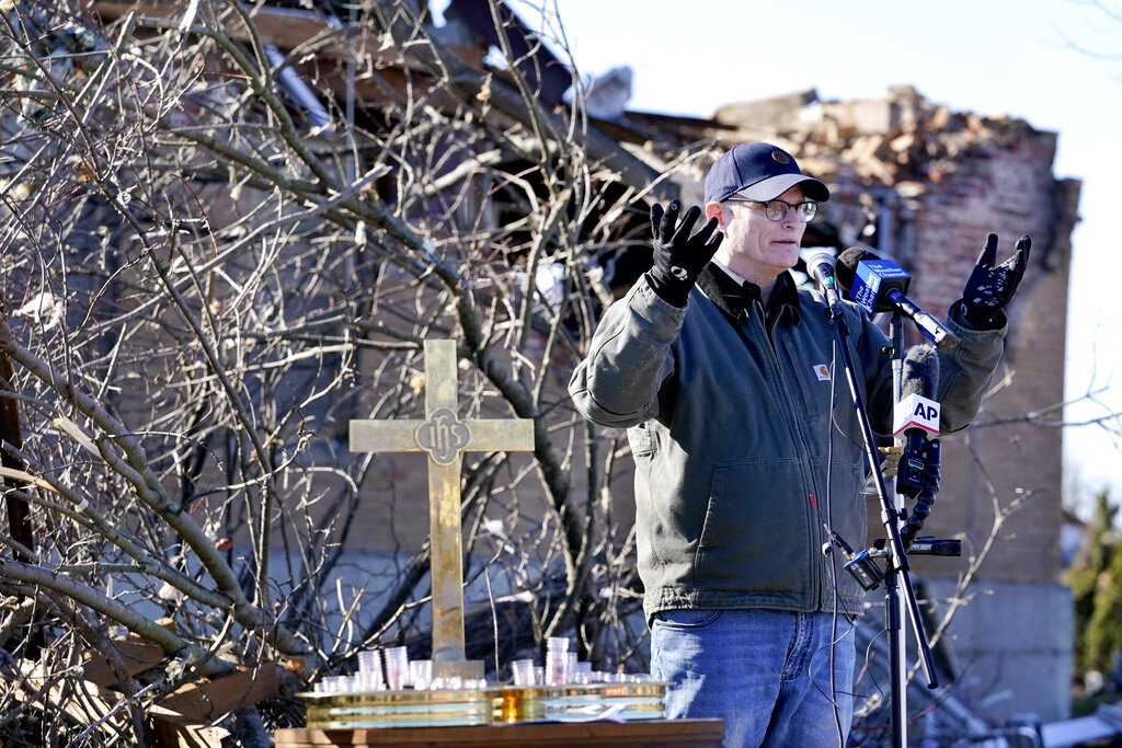 Dr. Milton West, senior minister of First Christian Church, speaks with the damaged church building behind him during an outdoor service Sunday, Dec. 12, 2021, in Mayfield, Ky. Tornadoes and severe weather caused catastrophic damage across several states Friday, killing multiple people. (AP Photo/Mark Humphrey)