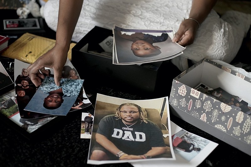 Carolyn Burnett sorts through mementos to select items to commemorate her son Chris Burnett on Sunday, Dec. 5, 2021, in Olathe, Kan. Chris Burnett, an unvaccinated 34-year-old father who coached football at Olathe East High School, died in September as a result of COVID-19 after nearly two weeks on a ventilator.  (AP Photo/Charlie Riedel)


