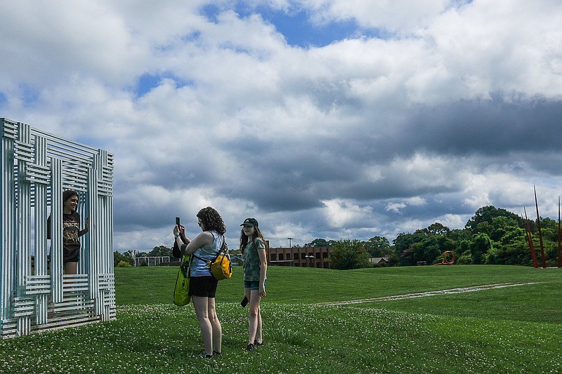 Staff file photo by Troy Stolt / Miranda Knittel of St. Louis smiles as Cara Pelikan takes a photo of her with a sculpture as her sister Jessica watches while visiting the Sculpture Fields at Montague Park on June 27, 2021. Located at 1800 Polk Street in the Southside, the now 33-acre public park features 40 large sculptures and a walking path.