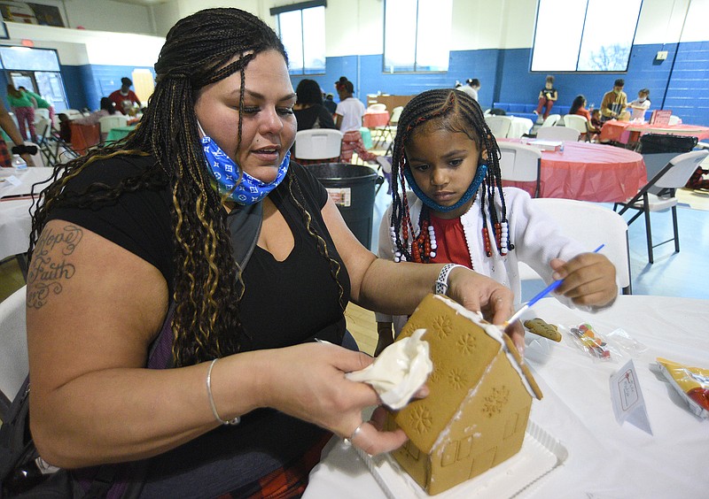 Staff Photo by Matt Hamilton / MaRie Robertson works with Raiven Woodruff, 6, as they make a gingerbread house at the Bethlehem Center during an event for Building Stable Lives program participants on Friday, Dec. 17, 2021.