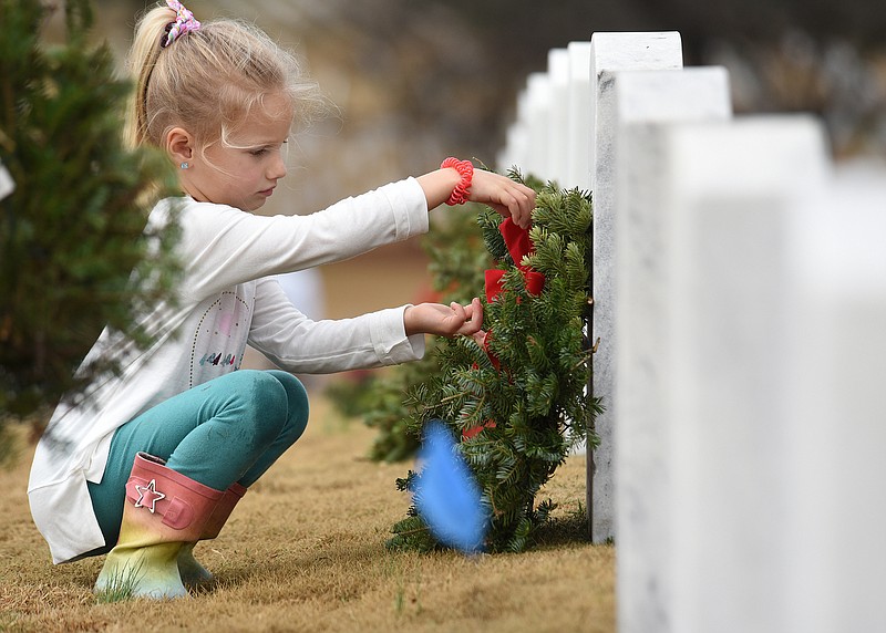 Staff Photo by Matt Hamilton / Hollyn Ford, 6, straightens the bow on a wreath at a grave at the Chattanooga National Cemetery on Saturday, December 18, 2021.