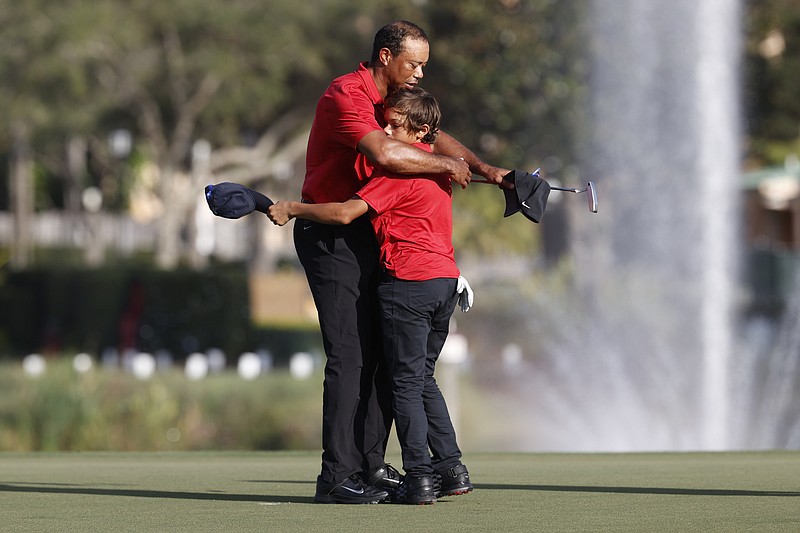 Tiger Woods hugs son Charlie Woods on the 18th green after the second round of the PNC Championship golf tournament, Sunday, Dec. 19, 2021, in Orlando, Fla. (AP Photo/Scott Audette)
