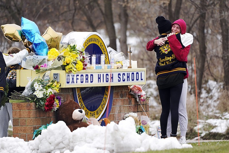 Students hug at a memorial at Oxford High School in Oxford, Mich., Dec. 1, 2021. School systems nationwide rely on high-level expertise from the U.S. Secret Service and others as they work to stay vigilant for signs of potential student violence, training staff, surveilling social media and urging others to tip them off. However, when it comes to deciding how to respond to a possible threat, it's the local educators who make the call. (AP Photo/Paul Sancya, File)