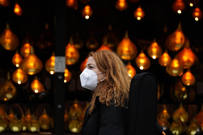 A woman wears a face covering as she passes a Christmas lights, in London, Wednesday, Dec. 22, 2021. British Prime Minister Boris Johnson said on Monday that his government reserves the "possibility of taking further action" to protect public health as Omicron spreads across the country. (AP Photo/Frank Augstein)