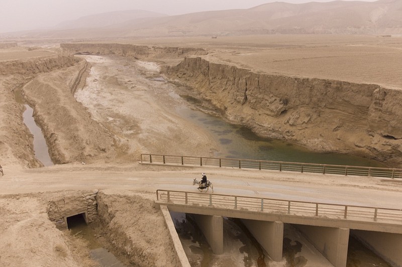 Afghan farmer uses donkey to carry water canisters across the dried-out river near Sang-e-Atash, Afghanistan, Monday, Dec. 13, 2021. (AP Photo/Mstyslav Chernov)

