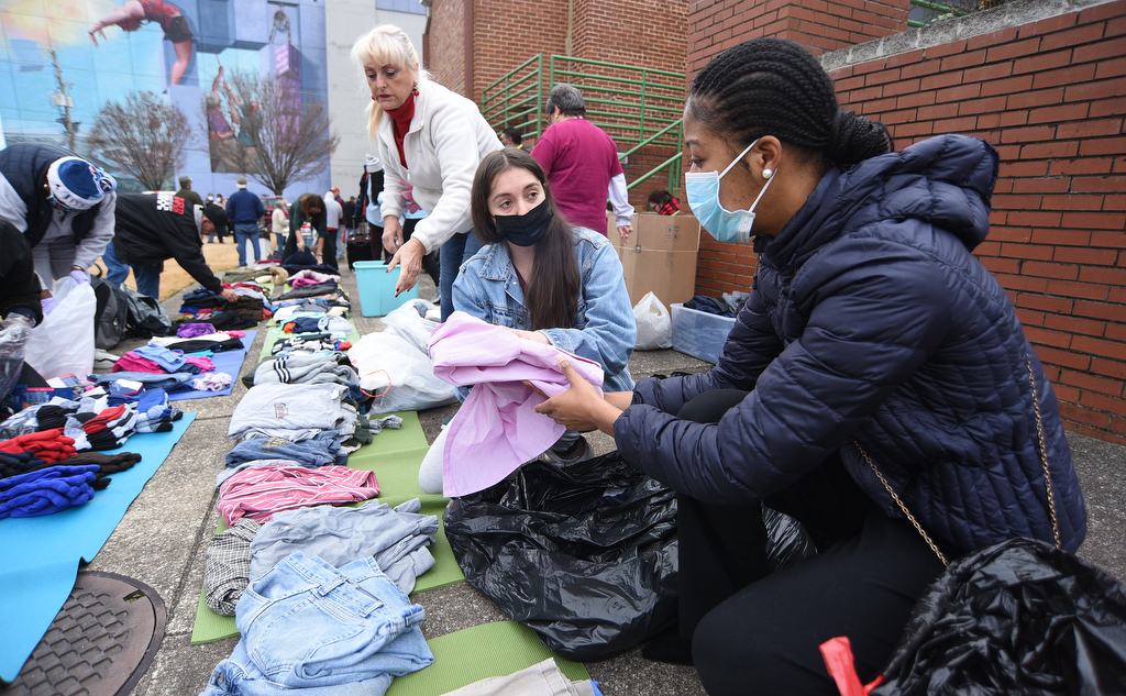 Staff Photo by Matt Hamilton / Cathleen Laskowski, back, Kelly Nel, and De'Jha Billingsley, front, lay out clothing to be given away at the Bessie Smith Cultural Center on Friday, December 24, 2021.