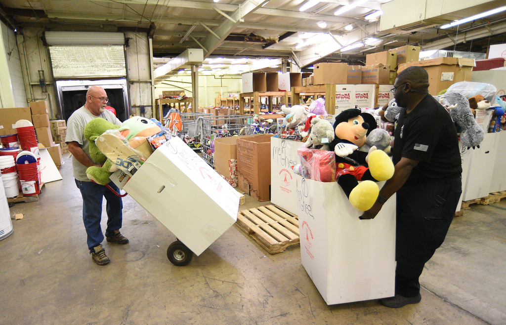 Staff Photo by Matt Hamilton / Dr. Troy Smith, left, and Sgt. David Young, right, load a truck with toys at the Forgotten Child Fund warehouse on Friday, December 24, 2021.