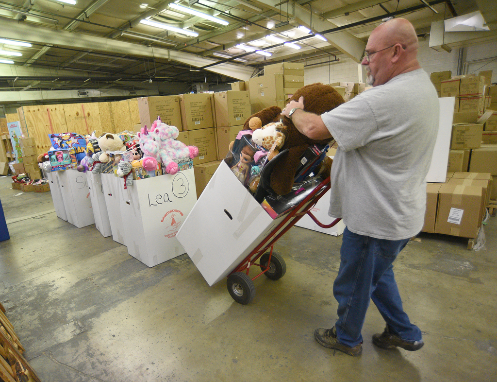 Staff Photo by Matt Hamilton / Dr. Troy Smith rolls a box of toys to be loaded on a truck at the Forgotten Child Fund warehouse on Friday, December 24, 2021.
