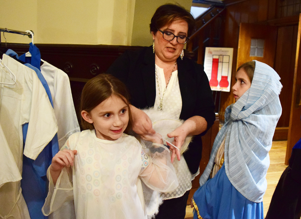 Staff Photo by Robin Rudd / Danielle Stradley helps daughter Hannah with her angel wings, while daughter Sarah, portraying Mary, ask a question, while they prepare for the Christmas Pageant. The Vigil Mass of Christmas was celebrated at the Basilica of Saints Peter and Paul on December 24, 2021.