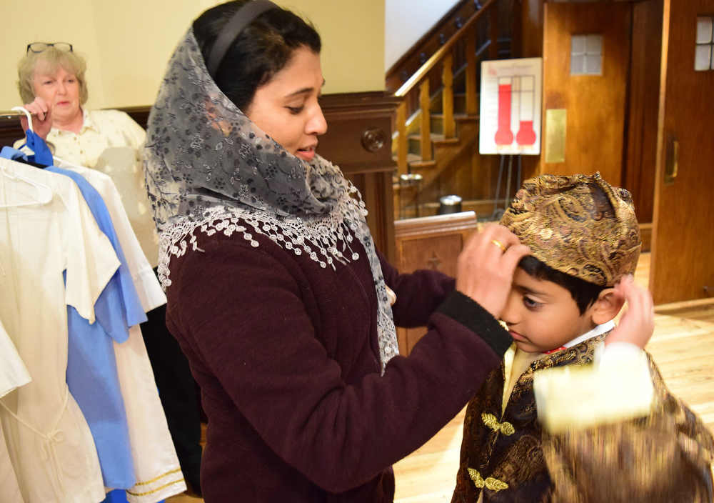 Staff Photo by Robin Rudd / Sheba Dominic helps her son, Francis, with his Three Kings costume. The Vigil Mass of Christmas was celebrated at the Basilica of Saints Peter and Paul on December 24, 2021.